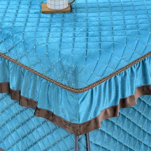 Detailed view of thick winter blue quilted heating table cover with elegant brown ruffled trim.