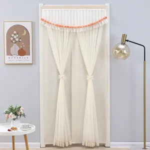 Detailed view of elegant white lace door curtain with pom-pom fringe and cute bow tiebacks.