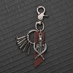 Detailed view of a retro alloy skull keychain with a brown leather strap and metal hook.