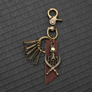 Close-up detail of vintage bronze alloy skull keychain with brown leather strap.