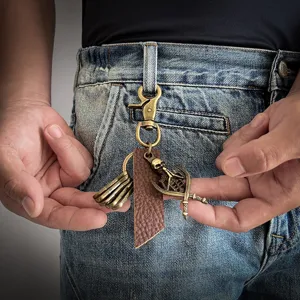 Retro bronze alloy skull keychain with leather strap shown on a denim belt loop
