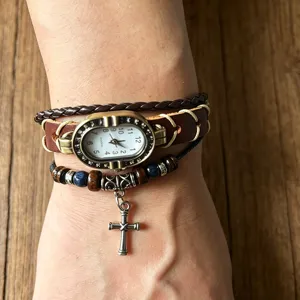 Close-up detail of vintage punk leather bracelet watch featuring silver cross pendant