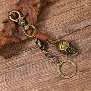 Zoom sur un porte-clés tête de mort en bronze vintage avec cordon en cuir et dé en métal