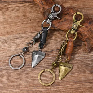 Detailed view of two vintage metal keychains featuring shark tooth and dice charms on wood