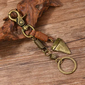 Detail of retro bronze keychain with shark tooth and dice pendant on wood background.