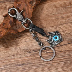 Close-up of vintage punk metal keychain with a blue evil eye pendant on wood background.