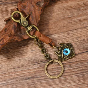 Close-up of a retro punk bronze keychain featuring a blue evil eye charm on rustic wood