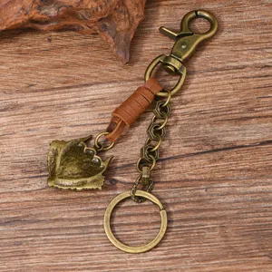 Detailed view of a vintage punk metal keychain with brown leather wrap on rustic wood.
