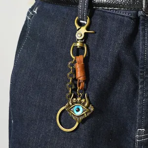 Close-up of vintage punk metal keychain featuring a blue evil eye and skull pendant