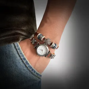 Close-up detail of a vintage punk style leather bracelet watch featuring a metallic cross charm