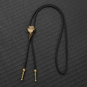 Detailed macro view of an antique bronze bird skull bolo tie with braided leather cord.