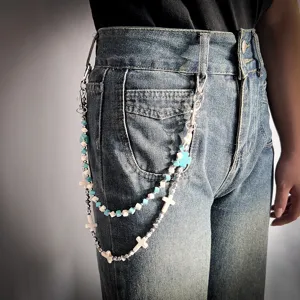 Detailed view of double-layered beaded trouser chain with turquoise beads and metal crosses.