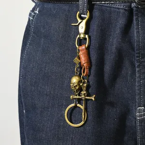 Detail shot of vintage punk skull metal keychain hanging on denim jeans.