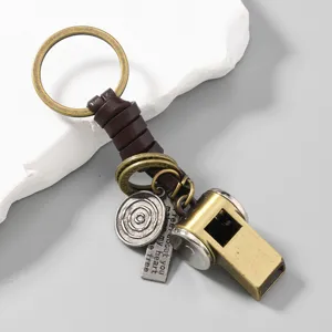 Detailed close-up of a retro brass whistle keychain featuring braided cowhide leather