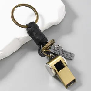Macro view of vintage bronze whistle keychain with engraved metal tag and leather cord