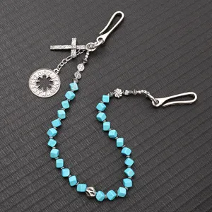 Détail d'une chaîne de taille punk avec pendentif croix et perles bleues