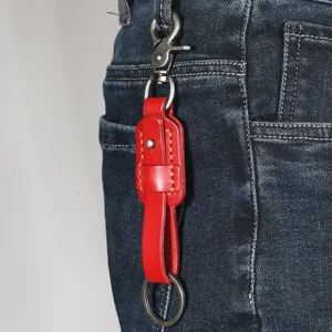 Macro detail of a red retro cowhide leather keychain hanging on blue denim jeans belt loop