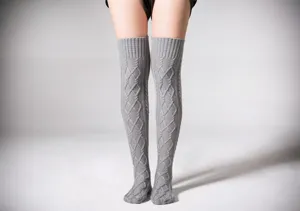 Close-up detail van grijze kabelgebreide overknee beenwarmers, zachte winterkniekousen.