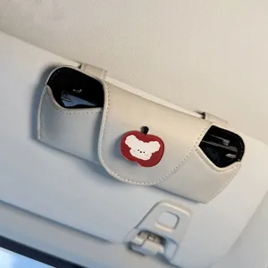 Detalle del soporte para gafas de sol de coche, cuero beis con bonita decoración de manzana.