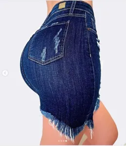 Detailed shot of women's dark blue denim skirt, high waist and tight fit with frayed hem.