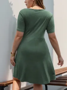 Detail view of a green ribbed short-sleeve plus-size casual mini dress worn by model outdoor.