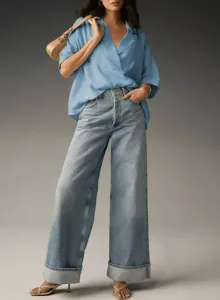 Detail view of the elegant loose lapel short sleeve shirt paired with trendy cuffed denim jeans.