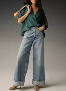 Detailed view of stylish green oversized short-sleeve shirt and wide-leg jeans outfit.
