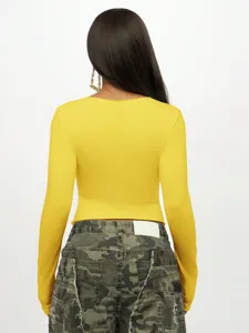 Detailed back view of a slim-fit yellow long sleeve crop top paired with camo pants.