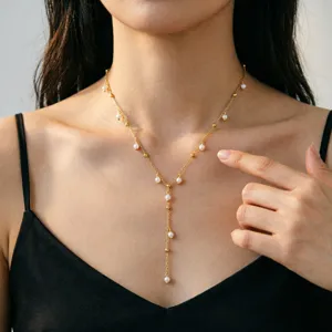 Detailaufnahme einer zarten goldfarbenen Y-Halskette mit Perlen an einem asiatischen Model.