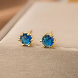 Nahaufnahme von eleganten goldenen Ohrsteckern mit blauen Steinen auf einer Schmuckschatulle.