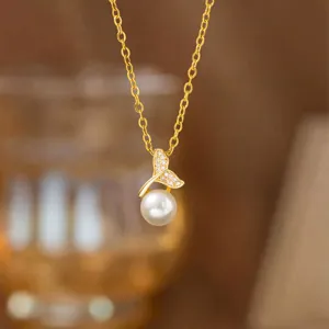 Nahaufnahme einer eleganten Goldkette mit zirkonbesetztem Muschel- und Perlenanhänger