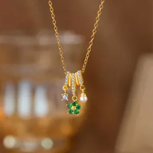 Nahaufnahme einer eleganten Goldkette mit grünem Blumenanhänger, Zirkon und Perlendetail