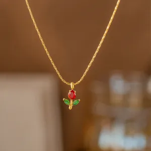 Makro-Detailansicht der eleganten goldenen Rosenanhänger-Halskette mit roten und grünen Zirkonia