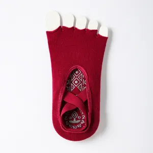 Red five toe yoga socks with non-slip silicone and cross straps, main view flat lay