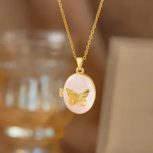 Detalle de un elegante collar con relicario de mariposa dorada y colgante de esmalte rosa