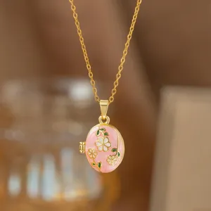 Primer plano de un colgante de relicario dorado con diseño floral de esmalte rosa