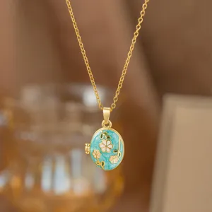 Primer plano de un collar relicario dorado elegante con detalle de esmalte floral azul claro