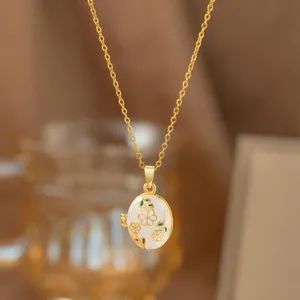 Elegante colgante guardapelo dorado con diseño floral y acabado en esmalte blanco