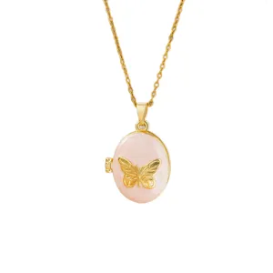 Detalle de un collar guardapelo de mariposa en esmalte rosa y dorado