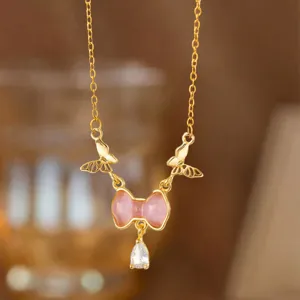 Detailaufnahme einer zarten Halskette mit rosa Schleife und glitzerndem Zirkon