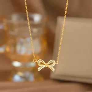Detailansicht einer eleganten goldfarbenen Halskette mit einem feinen Schleifenanhänger