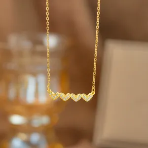 Detailaufnahme einer Goldkette mit vier mikrogepflasterten Herzanhängern