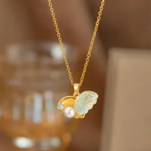 Detaillierte Nahaufnahme einer goldenen Muschelkette mit weißer Perle und blauem Emaille