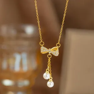 Nahaufnahme einer goldenen Schleifenkette mit Zirkonia und Perlenanhängern.