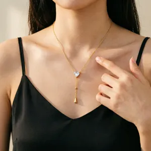 Elegante goldene Y-Quastenhalskette mit Herzkristall-Anhänger, getragen von einem Modell