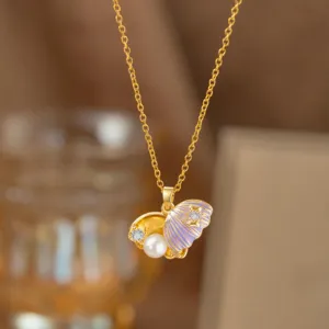 Makro-Detail einer Goldkette mit lila Emaille-Muschel-Anhänger und Perle