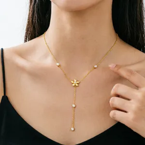 Nahaufnahme einer eleganten goldenen Y-Blumen-Quastenkette am Hals eines weiblichen Models