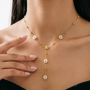 Detailansicht einer goldenen Y-Halskette mit Fransen und zarten weißen Perlenblumen.