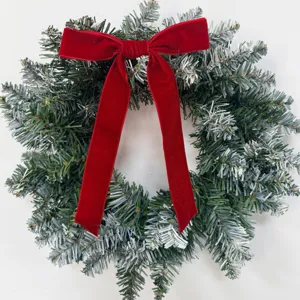 Detailansicht eines festlichen Weihnachtskranzes mit einer großen roten Samtschleife für Feiertage.