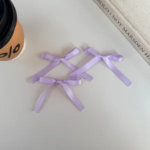 Primer plano de lazos de cinta de satén violeta claro, textura lisa, ideales para envolver regalos.